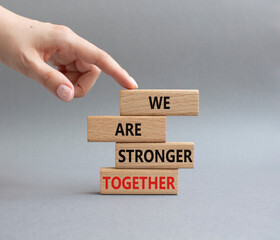 We are stronger together symbol. Wooden blocks with words We are stronger together. Businessman hand. Beautiful grey background. We are stronger together concept. Copy space.