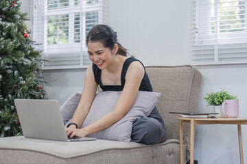 Smiling young woman using laptop, sitting on couch at home, beautiful girl shopping or chatting online in social network, having fun, watching movie, freelancer working on computer project