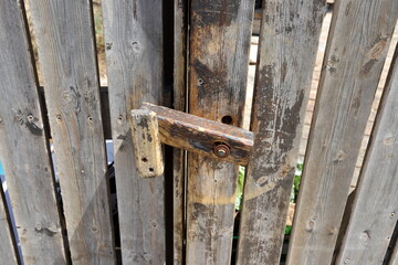 An old metal lock hangs on the fence.