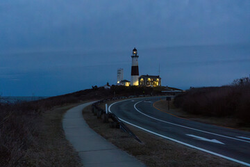 Faro iluminado al atardecer en una carretera costera