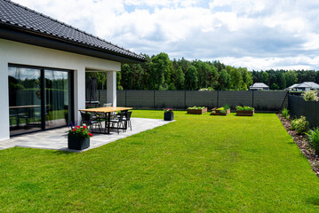 A modern table made of raw wood covered with yacht varnish, standing on the garden terrace.