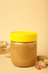 Tasty peanut butter in jar on beige background