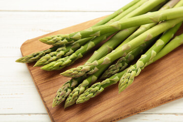 Fresh green asparagus on cutting board on light background. Healthy food concept. Vegan healthy food.
