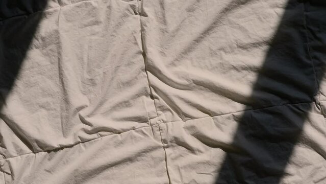 female hand reaching for a pink sex toy rabbit shaped vibrator for women in bed, sun rays on a blanket, good morning bedroom concept