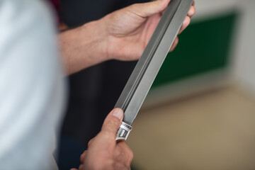 The blade of the saber. Hands of a dagger maker at work, close-up.