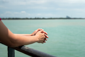 Close-up at people arm and hand part during leaning on handrail at the passenger deck to ferryboat with blue ocean background. Transportation for travel concept scene. 