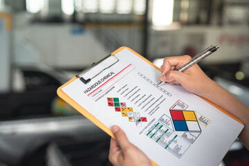 Action of a safety supervisor hand is checking on checklist of chemical and hazardous material form...