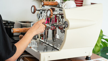 Action of a barista is making fresh coffee by using automatic coffee machine. Close-up and selective focus.