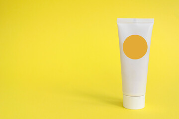 White cream tube with spf product on a yellow background. Beauty UV concept, clean and care cosmetics.