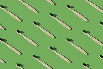 Organic bamboo toothbrush pattern composition on green background. Minimal dental concept. Creative eco friendly, biodegradable and natural wooden toothbrush pattern background idea.