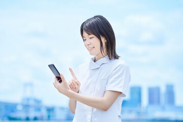 白衣を着てスマートフォンを操作する若い女性
