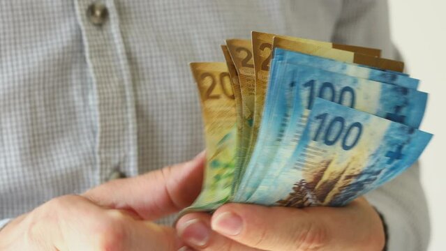 Man counts a stack of Swiss francs, financial concept