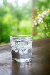 a glass of cold water with ice on rustic table.