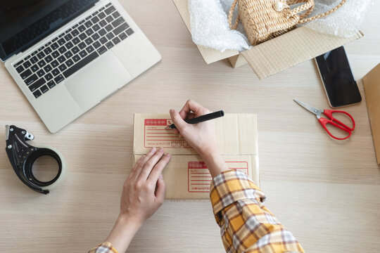 Efficiently preparing packages for seamless shipping. The hands of an online store meticulously pack and protect products, ensuring a smooth fulfillment process for satisfied customers worldwide.