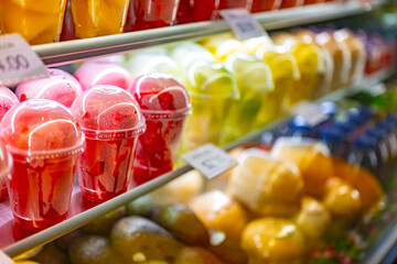 Plastic cups with fresh fruits displayed in a refrigerator
