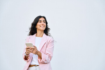 Smiling young middle eastern businesswoman using smartphone mobile phone app for work isolated on white background. Indian or arabic woman in business suit holding cellphone, looking aside. Copy space