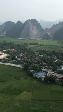 drone view of small town and gas station surrounded by a road near crop fields and mountains in hanoi vietnam