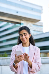 Young middle eastern Israel businesswoman using smartphone mobile phone online app for work at office building. Successful smiling indian or arabic woman in business suit holding cellphone. Vertical