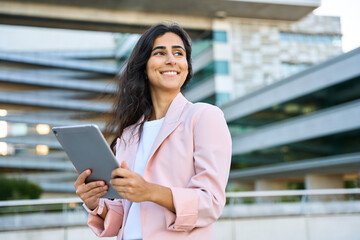 Portrait of young middle eastern Israel businesswoman using tablet pc application for work at office business building outdoors. Indian arabic woman holding digital computer, looking aside. Copy space