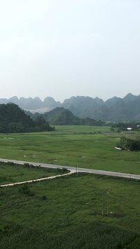 bird's eye view of the road surrounding the crop fields near the green mountains and jungle of hanoi vietnam