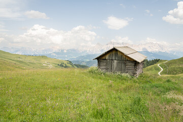 Beautiful summer view on alpine meadow with a wooden barn near the Peitlerkofel mountain. ( Sass de Putia) Idyllic scenery, Alpine meadow in the foreground, rocky Italian mountains in the background. 