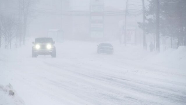 Winter and snow storm in Dartmouth, Canada. Cars drive along the roadway of the city in a heavy snowstorm, the roads are covered with snow and ice. 2024