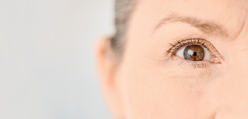 Eye, vision and woman in studio for care, testing and healthcare on gray background. Senior person, portrait and face with contact lenses for sight, optometry and optical assessment by specialist
