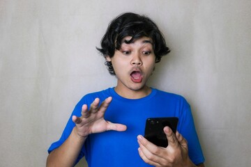 Fototapeta premium portrait of a very attractive random handsome Asian Indonesian man on a white isolated background wearing blue clothes