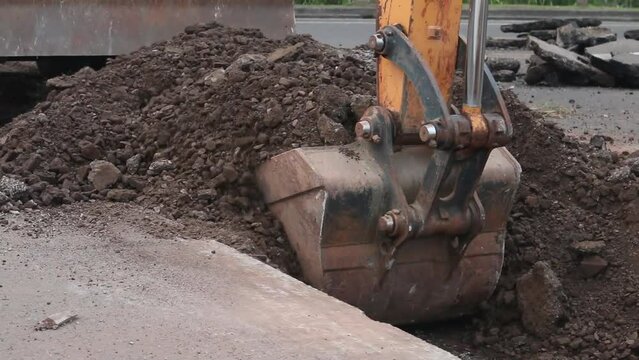 Excavator digs trench in the construction site, close up backhoe digger