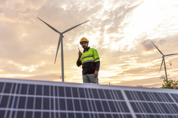 Professional Man Maintenance engineers working in wind turbine farm at sunset.  Engineer Man standing among Wind Energy Turbine.