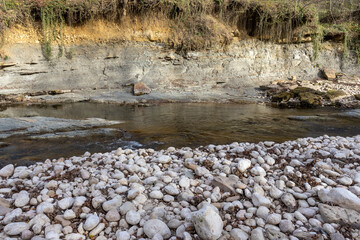 the texture of the riverbank with a stone bed and a leisurely flow, autumn park