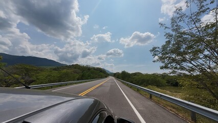 family traveling in a car walking on a road with a forest and mountains in the background on a sunny day on a trip on vacations