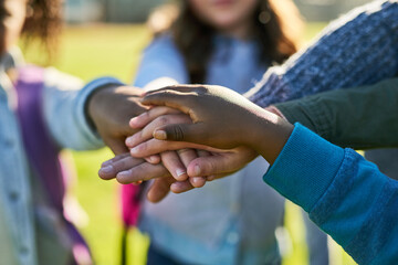 Kids, hands and huddle as friends together outdoor for youth development, support and solidarity. Children, teamwork and diversity for trust, collaboration and community as people with social bonding
