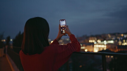 Unknown woman photographing cityscape using smartphone at night square closeup