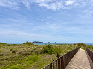 Fototapeta na wymiar View over a wooden walkway and the dune landscape to the rocks Illes Medes in the Mediterranean Sea, L'Estartit, Platja de l'Estartit, Girona, Catalonia, Costa Brava, Spain