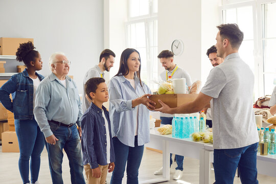 Group of diverse poor people getting food aid at a non profit organization center. Team of volunteers giving multiethnic needy citizens food and hygiene supplies. Help, charity and donation concept