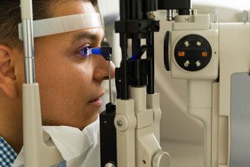 Profile view of a patient getting his eye pressure checked by and ophthalmologist using state of...