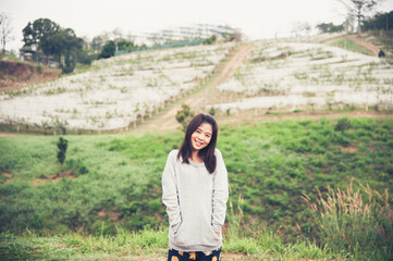 Young asian lady standing and smiling with green backgound outdoor on vacation
