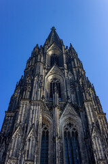 Gothic spires and ornaments of Hohe Domkirche St. Petrus (Cologne Cathedral) under blue sky in Cologne, Germany