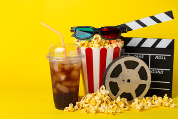 Tasty popcorn in buckets and cold cola drinks with cinema tickets, movie clapper and 3D eyeglasses...