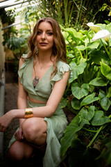 Obraz premium A beautiful young woman is holding a large green leaf. Hot sunny day. Rest on a tropical island. Summer travel girl, active lifestyle