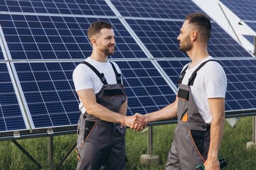 Two bearded workers in overalls shake hands after completing a panel plan
