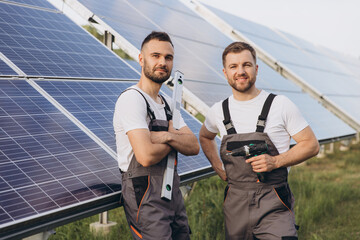 Two bearded technicians servicing solar farm panels looking at camera while holding tools