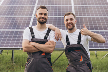 Two bearded men technicians professionals servicing solar farm standing with crossed arms and...
