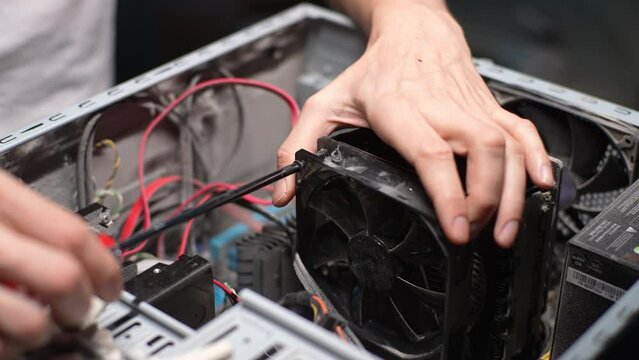 Computer repair technician tightening unscrews screws inside of desktop PC with screwdriver for disassembling heatsink of PC central processor cooling. Concept of service for repair and cleaning PC.