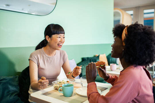 Diverse female employees eating lunch together in office