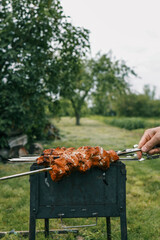 Man hand grilling barbecue with smoked pork at backyard on day. Family dinner outdoor style bbq activity