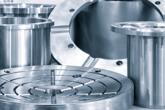 A collection of metal parts, including a round piece with a hole in the middle. Concept of precision and engineering, as the various parts are arranged in a neat and organized manner