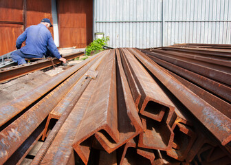 rusty steel profiles stored outdoors, worker steel production