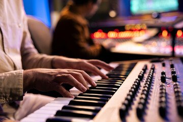Artist performer recording his song on electronic keyboard piano, working with audio engineer in...